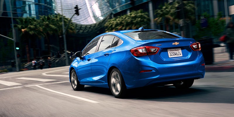 Blue Chevy Cruze driving in modern cityscape