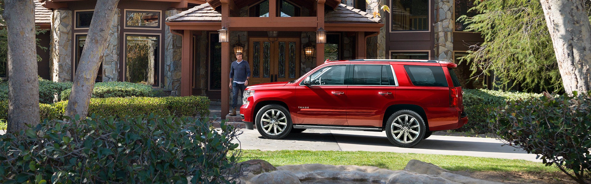 Red Chevrolet Tahoe parked in front of nice hotel entrance