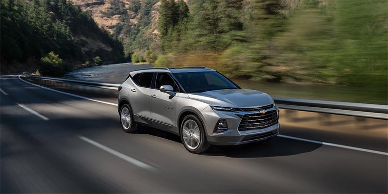 Silver Chevrolet Blazer driving fast on country road