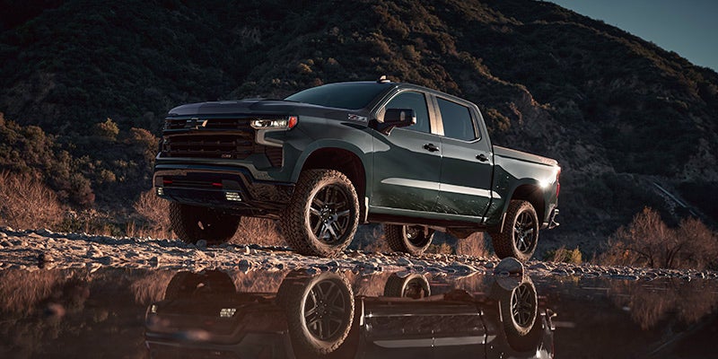 Chevy Silverado driving through dirt road while sun is setting