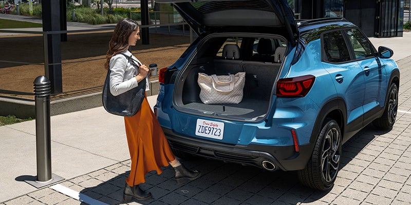 Chevy Trailblazer parked on the street as a woman who is smiling opens the back trunk