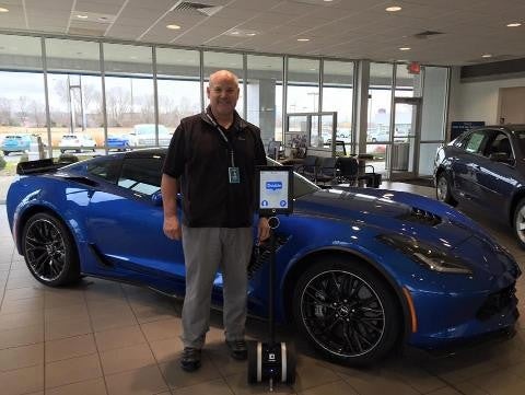 Murdock Manhattan Chevrolet salesman standing in front of a blue corvette
