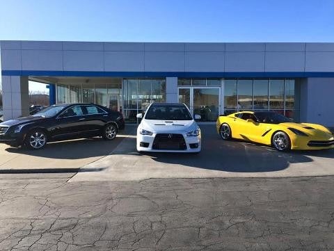 Outside view of Murdock Manhattan Chevrolet dealership with 3 different type of Chevrolet vehicles
