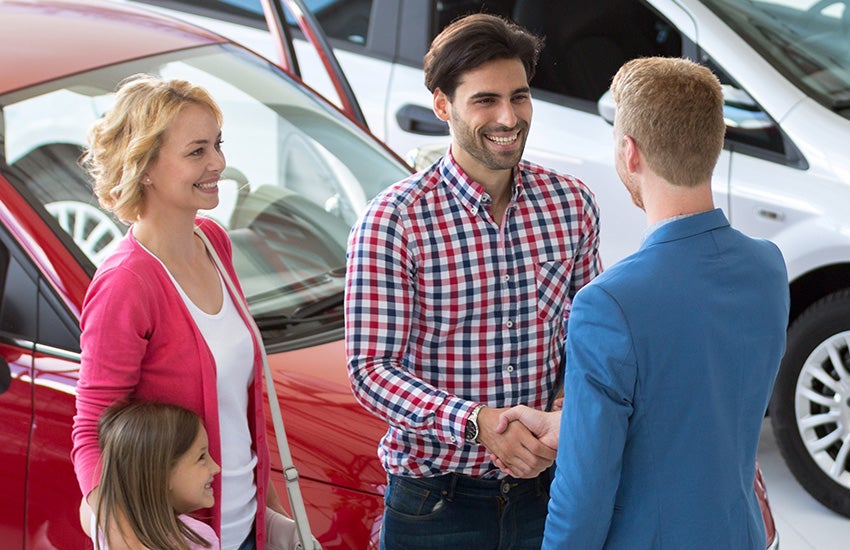 Murdock Manhattan Chevrolet salesman shaking hands with family to introduce himself and showcase used car inventory