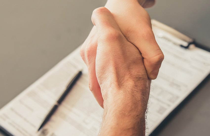 Two people shaking hands after they agree on what maintenance should be done to the vehicle at Murdock Manhattan Chevrolet