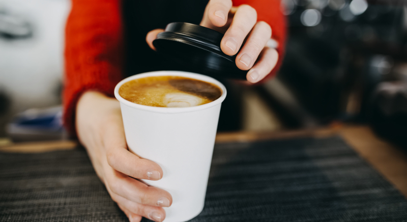 Barista handing a customer a fresh warm coffee at the counter