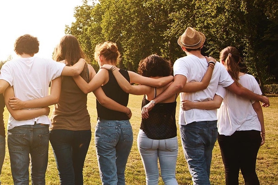 group community hugging each other outside while the sun is setting