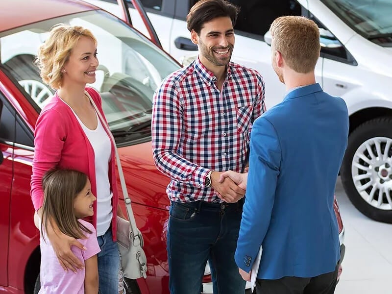 Sales manager shaking hands with the family after they time their trade in perfectly