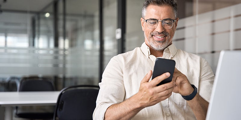 Older gentleman using his smartphone to contact Murdock Manhattan Chevrolet for a Chevrolet vehicle
