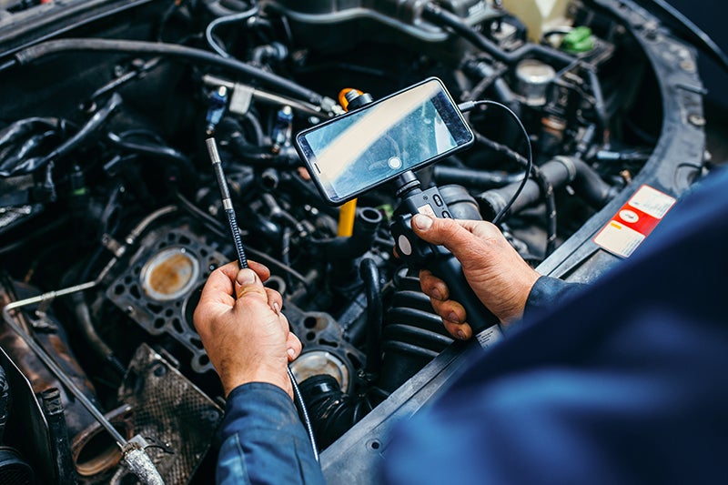 Mechanic using a camera to video inspect all the parts of the engine