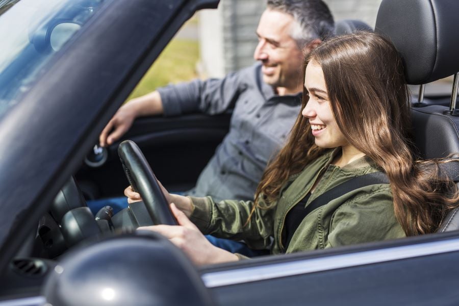 Happy teen driver with her father driving to Murdock Manhattan Chevrolet