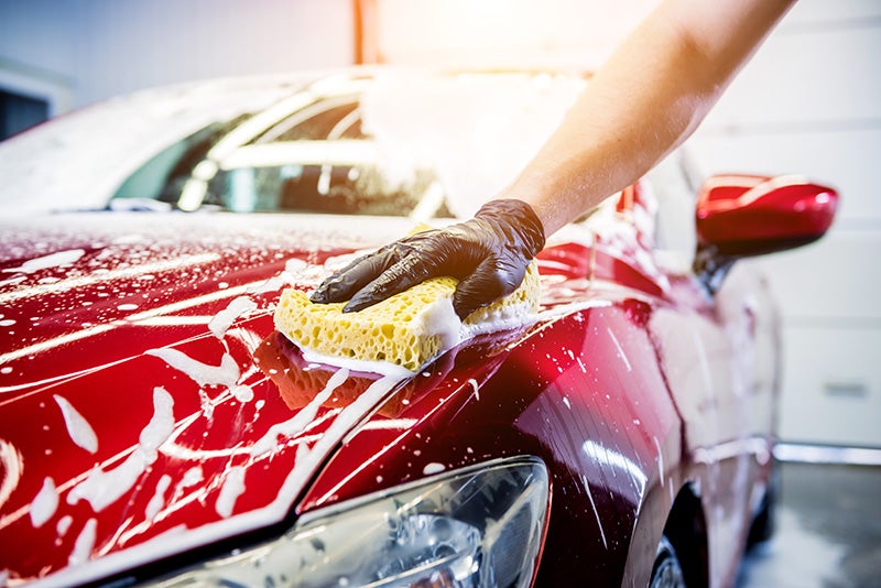 Detailer washing the car with a sponge and soap